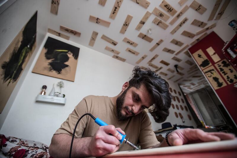 Saif Al Mallah, an Iraqi artist and refugee in Paris, works on a pyrography artwork about his memories in Mosul, in his room in Paris, France. EPA