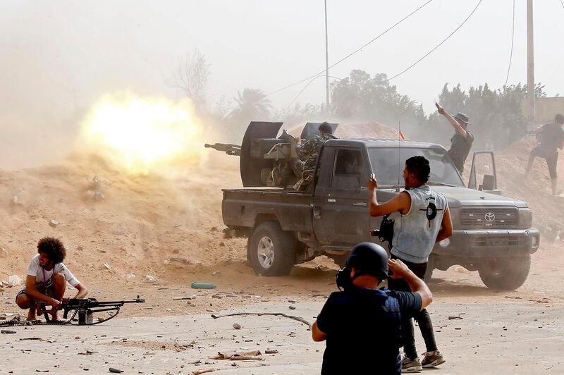 A fighter loyal to the Libyan internationally-recognised Government of National Accord (GNA) fires a heavy machine gun as a press photographer take pictures of the scene during clashes against forces loyal to strongman Khalifa Haftar, on May 25, 2019, in the Airport Road Area, south of the Libyan capital Tripoli. / AFP / Mahmud TURKIA
