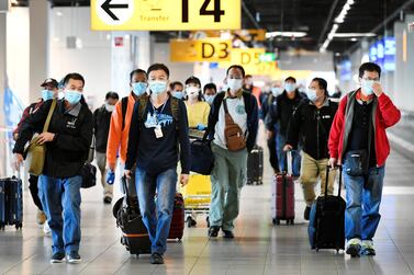People wearing protective face masks walk through Schiphol Airport in Amsterdam, The Netherlands. Reuters