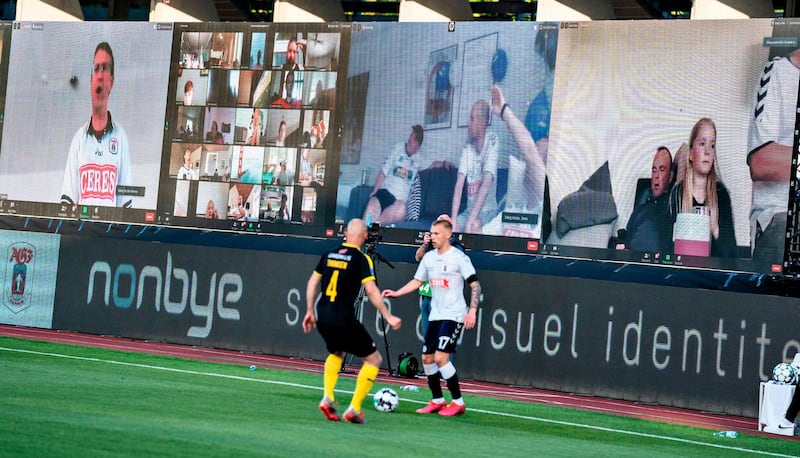 Players vie for the ball as fans are streamed live on to the screens on the sidelines during the 3F Super League football match between AGF and Randers FC. AFP