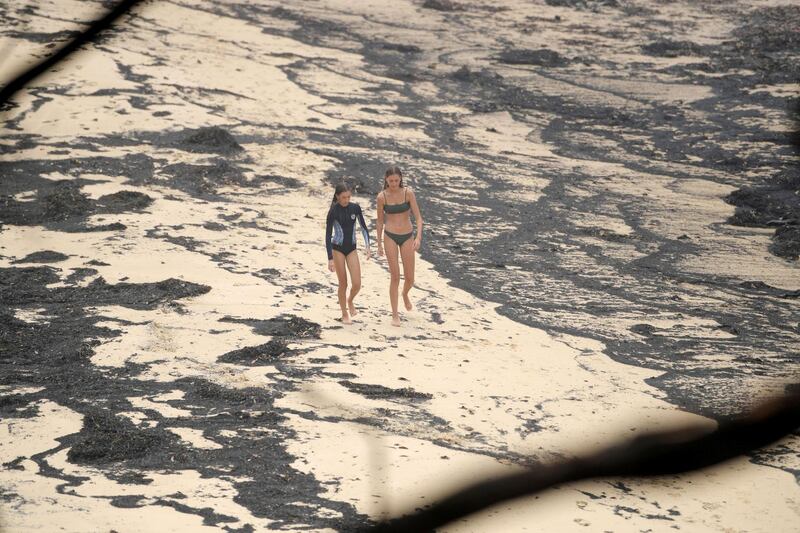 Girls walk past ash washed up on a beach where people took shelter during a fire on New Year's Eve in Mallacoota, Australia. Reuters