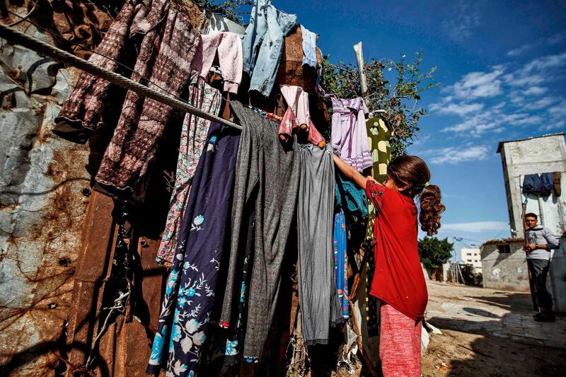A Palestinian girl hangs clothes out to dry on a line outside her home in Gaza City.  AFP
