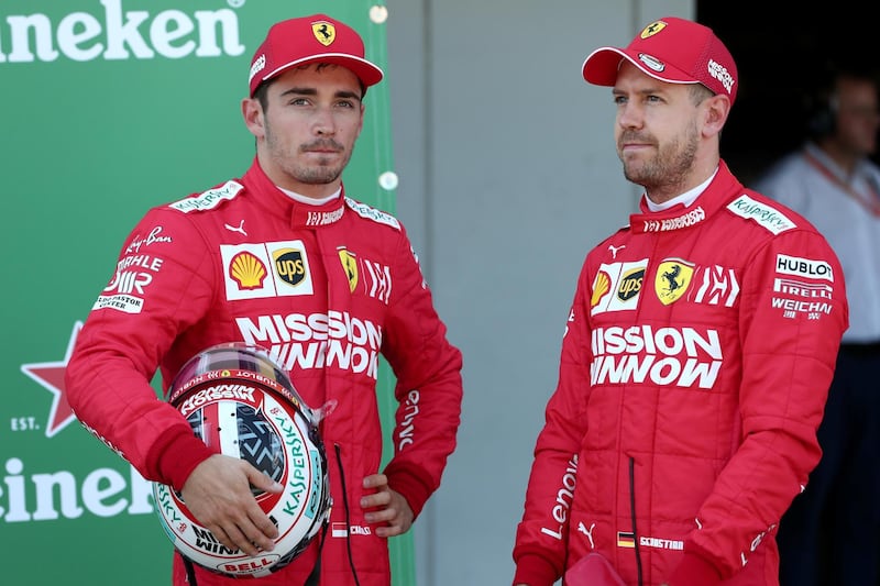 Ferrari's German driver Sebastian Vettel (R) stands with Ferrari's Monegasque driver Charles Leclerc (L) after finishing first and second respectively in the qualifying session for the Formula One Japanese Grand Prix at Suzuka on October 13, 2019. (Photo by Behrouz MEHRI / AFP)