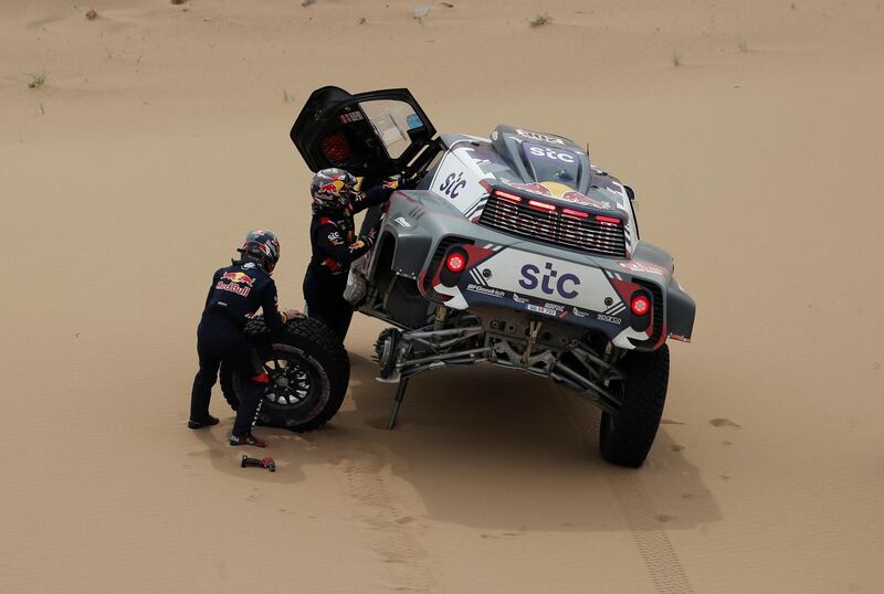 Stephane Peterhansel and  Edouard Boulanger change a tyre during Stage 11. Reuters