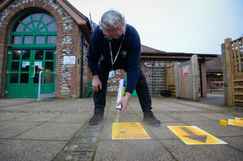 Caretaker Paul Bascombe marks safety signs for social distancing at The Prince of Wales School in Dorchester. Getty Images