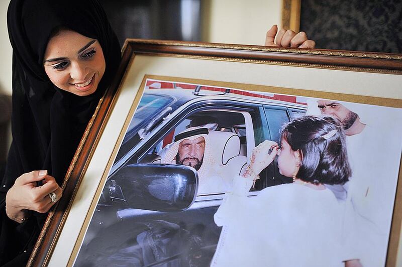 An Emirati lady showing a picture of herself as a young girl, meeting Sheikh Zayed.