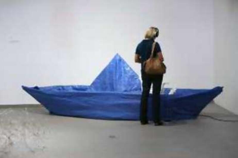 DUBAI, UNITED ARAB EMIRATES - DECEMBER 11:  A woman checks out a piece by Elizabeth Monolan and Robert Ferry called "The World's Largest Blue Tarp Origami Boat" on display at an exhibit entitled ÒIn SituÓ featuring art sculptures and installations by artists living in the UAE at the Jam Jar in Dubai on December 11, 2008.  (Randi Sokoloff / The National)  For story by Sarah Woolf for A&L *** Local Caption ***  RS014-1211-InSitu.jpgRS014-1211-InSitu.jpg