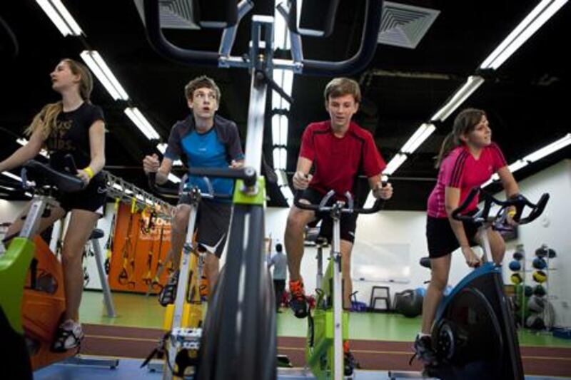 Left to right, friends Emma Clout, 12, Tom Verdon, 14, Josh Clout, 14, and Megan Tremblay, 12, get some exercise on stationary bikes while spending time indoors on Saturday, June 11, 2011, at the Haddin's Gym in Zayed Sports City in Abu Dhabi, one of few sport venues that caters to children and teens.  (Silvia Razgova / The National)

Names, all CQ:

Tom Verdon, 14, (blue eyes, dark hair)
Megan Tremblay, 12, (dark hair, pink and later grey top)

Olivia Wright, 12,(Helena Frith-Powel's eldest daughter)
Bea Wright, 10, (Helena Frith-Powel's middle daughter)
Leonardo Wright, 7, (Helena Frith-Powel's son) 

Helping children at the ice rink:
Zahra Lari, 16, UAE (in sheila)
Alexa Joyce, 13, UK (with glasses, dark long hair)
Cecilia Joyce (Alxa's mother, short dark hair)
Noemi Bedo, Romanian, Assistant Head Coach for the AD Figure Skating Team (sandy hair, Caucasian)