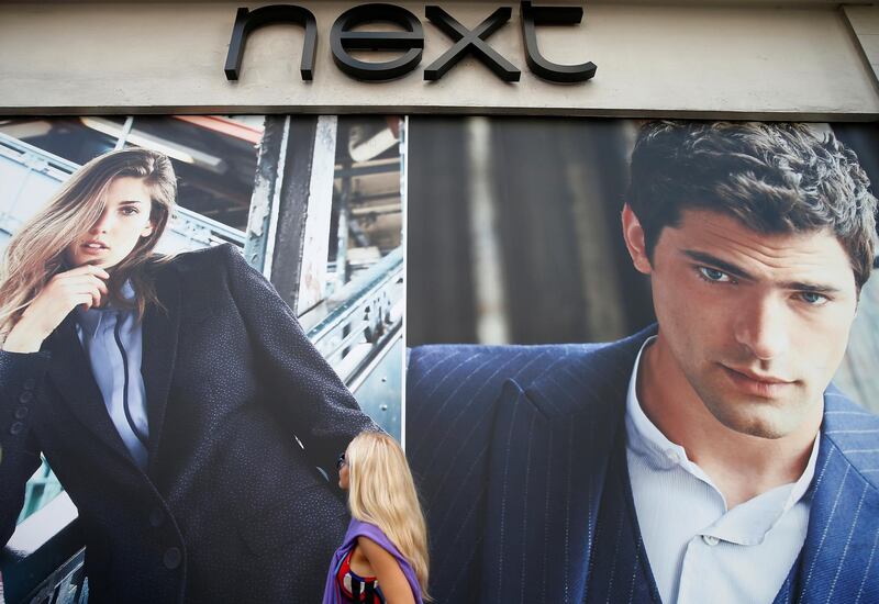 FILE PHOTO: A woman walks under advertising outside a branch of clothing retailer Next in London, Britain September 30, 2014.  REUTERS/Andrew Winning/File Photo