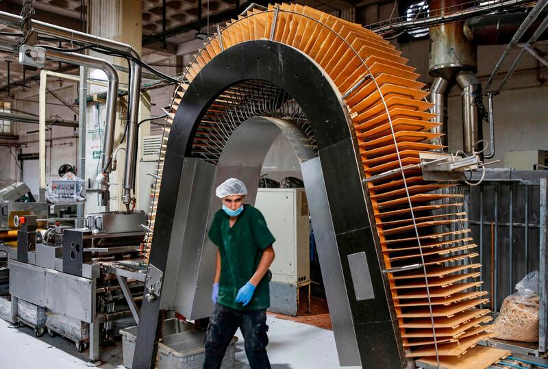 A Palestinian industrial worker walks through the arch of a wafer sheet production line at a biscuit factory in the West Bank city of Ramallah.  AFP