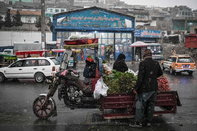 A vendor sells vegetables during the snowfall.