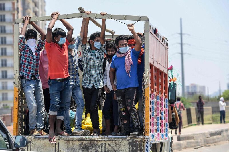 Migrant workers and families onboard a truck wait to cross the Delhi-Uttar Pradesh border to go back to their native places after the goverment eased a nationwide lockdown imposed as a preventive measure against the COVID-19 coronavirus, in New Delhi on May 16, 2020.  / AFP / Prakash SINGH
