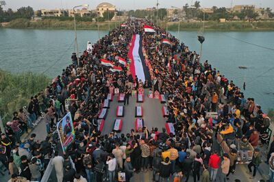 Iraqis carrying posters of killed anti-government protesters attend a march to honour the memory of the protesters killed in 2019, at the Zeitoun bridge, near Habboubi Square in Nasiriyah. AFP
