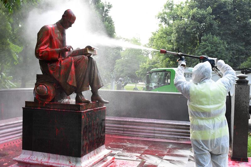 A municipal employee cleans a statue of a famous Italian journalist Indro Montanelli in a Milan public square, a day after it was defaced. AFP