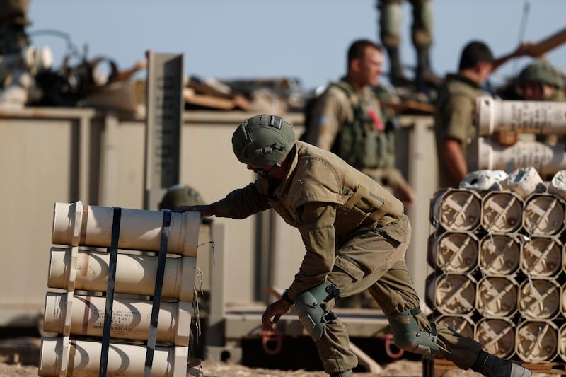 An Israeli artillery soldier carries shells as their unit aims at targets in the Gaza Strip. EPA