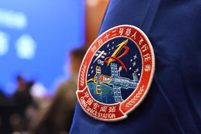 A staff member of the Jiuquan Satellite Launch Centre wears the logo of China's new space station during a press conference about the first crewed mission to the station, scheduled for June 17, at the Jiuquan Satellite Launch Centre in the Gobi desert in northwest China on June 16, 2021.  / AFP / GREG BAKER
