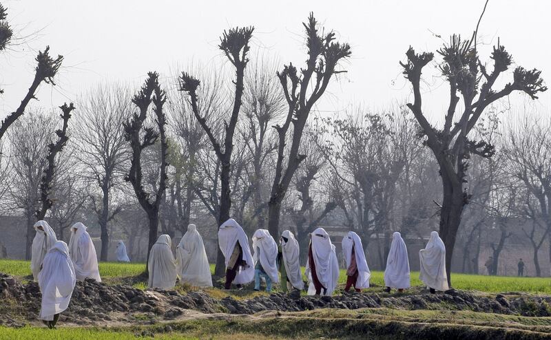 Women walk near the site of an attack on the outskirts of Peshawar, Pakistan, on February 12, 2014. Militants killed several members of an anti-Taliban militia in the northwestern city, police said. Mohammad Sajjad / AP photo