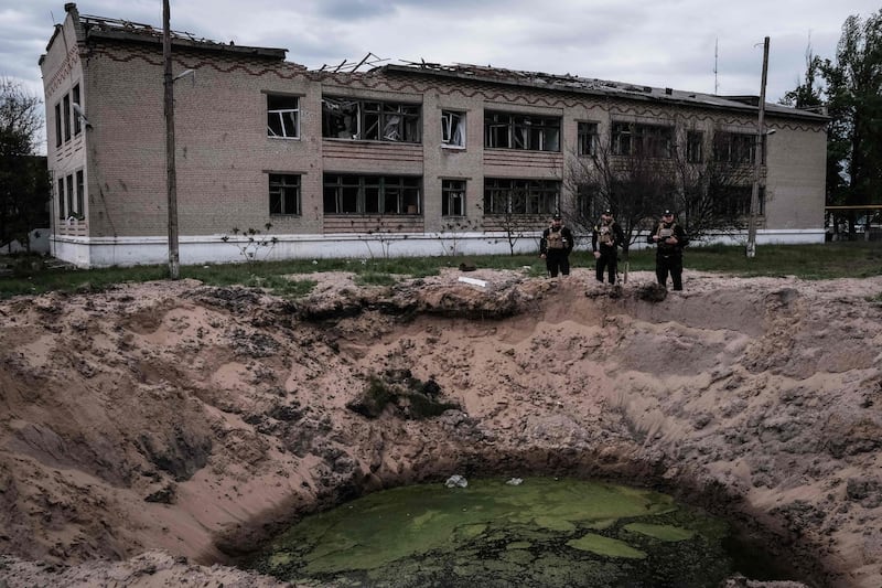 Three Ukrainian policemen stand at an explosion site in Novomykolaivka, eastern Ukraine. AFP