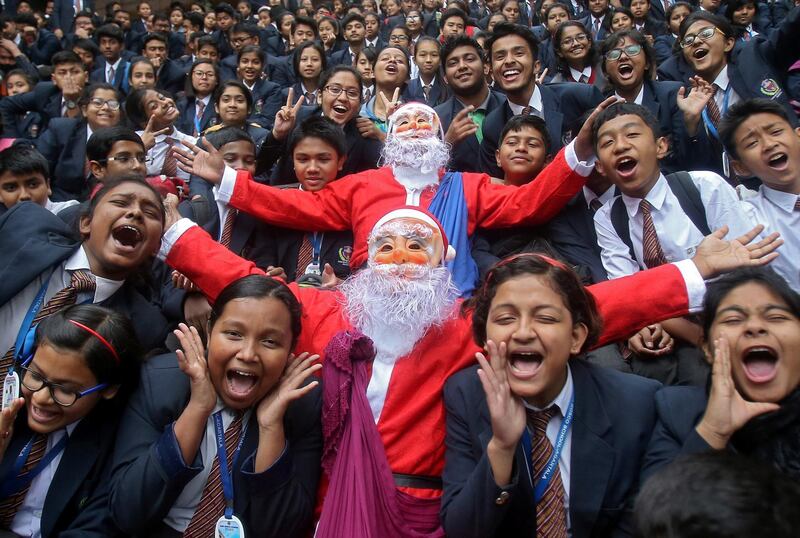 Children cheer around men dressed as Santa Claus during Christmas celebrations inside their school in Agartala, India. Reuters