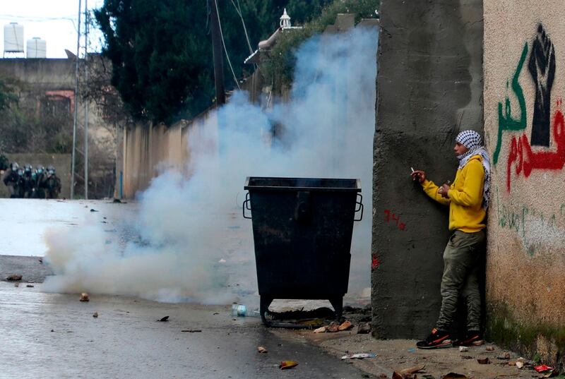 A Palestinian man takes cover during clashes with Israeli troops and Palestinian protesters in the village of Kfar Qaddum near the Jewish settlement of Qadumim (Kedumim) in the occupied West Bank. AFP