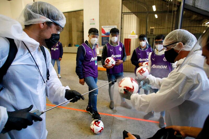 A worker disinfects a ball before the start of a Mexican tournament football match between Guadalajara and Atlas in Guadalajara, Jalisco state, Mexico. AFP