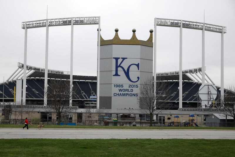 A woman and her dog walk past Kauffman Stadium, home of the Kansas City Royals baseball team, on March 25, 2020, in Kansas City, Missouri. AP Photo