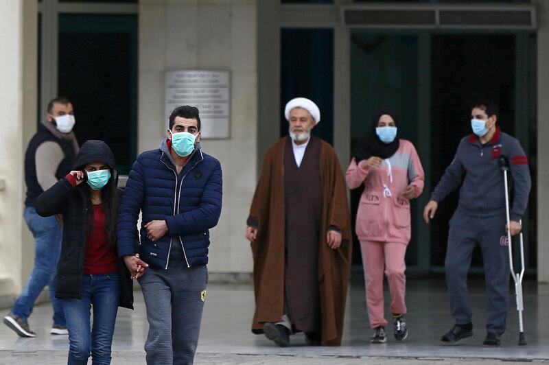 People wear face masks as they walk outside of the Rafik Hariri University Hospital where a woman is treated for coronavirus, the first case in Beirut, Lebanon.  EPA