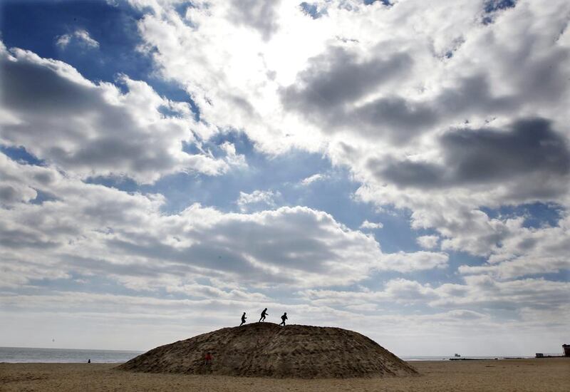 Children play on a large mound of sand on the beach early Sunday in Asbury Park, New Jersey. Mel Evans / AP Photo