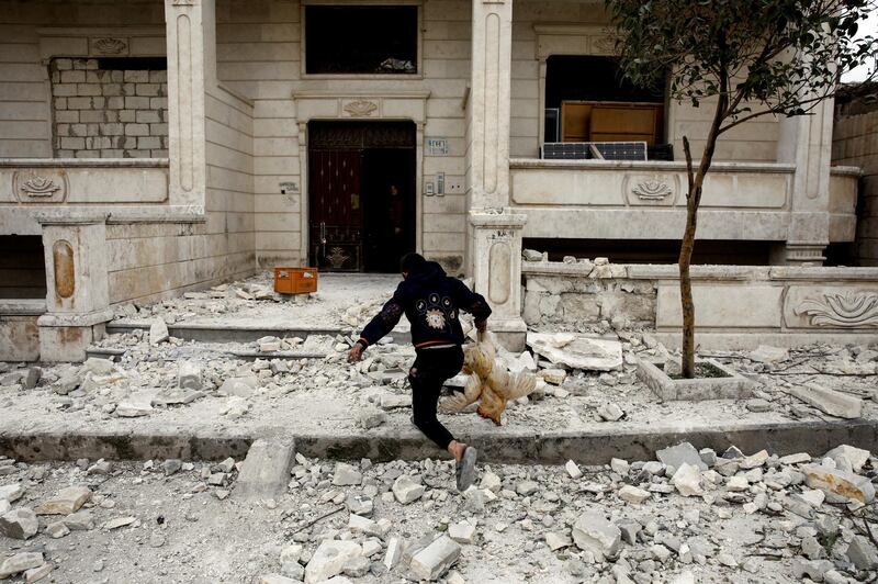 A Syrian boy removes a dead chicken from the debris of a building hit by an air strike in Idlib, Syria. REUTERS