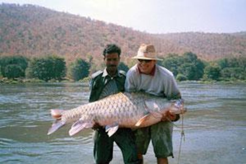 A man struggles under the weight of a mahseer caught in Karnataka.