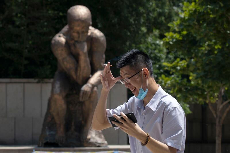 A man lowers his mask to smoke as he passes by a statue in Beijing, China. AP Photo