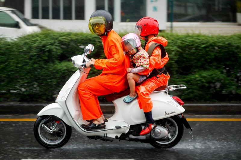 A family rides a motorcycle during heavy rain in Bangkok, Thailand. Diego Azubel / EPA