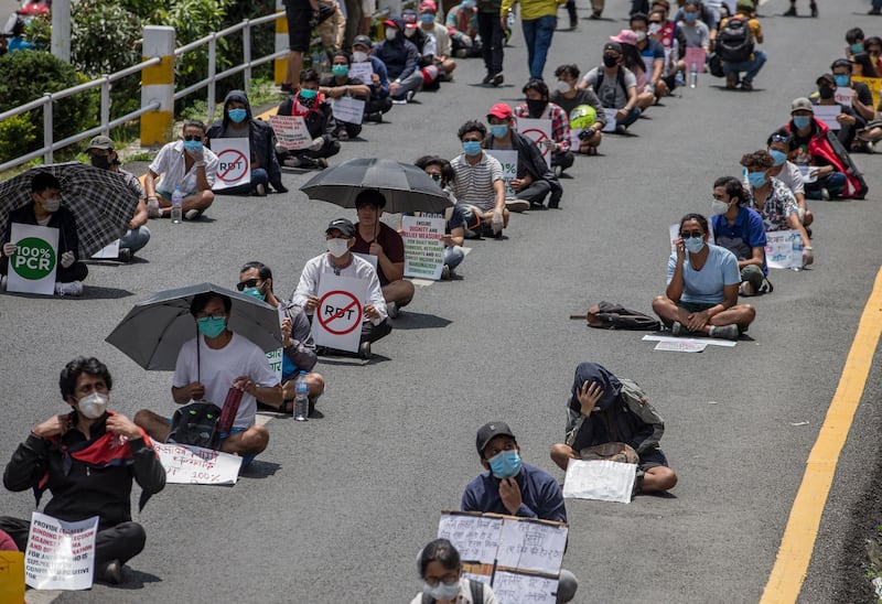 Demonstrators sit on the ground with placards during a coronavirus protest in Kathmandu, Nepal.  EPA