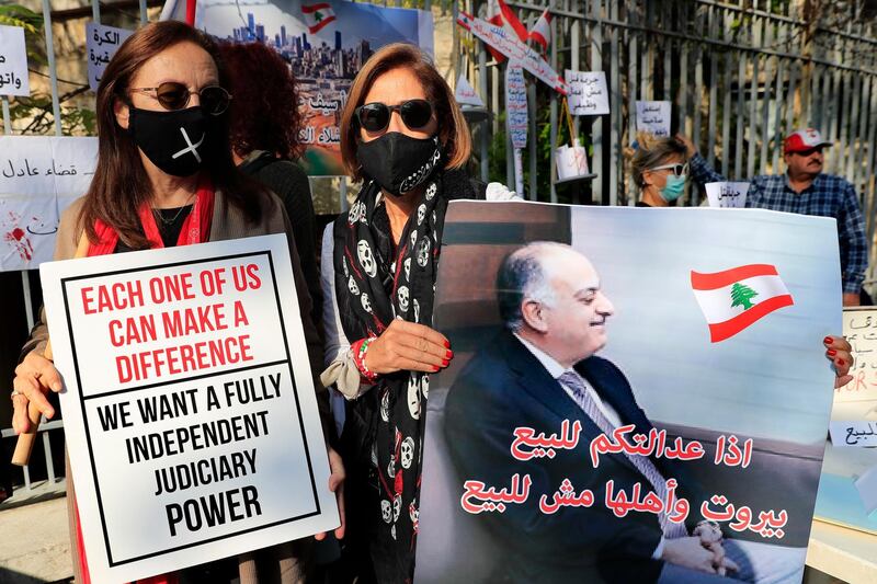 A Lebanese activists holds a placard showing a portrait of Lebanese judge Fadi Sawan who is in charge of the investigation of the August explosion in Beirut, with Arabic that reads: "if your justice is for sale, Beirut and its people not for sale," during a protest outside the justice palace, in Beirut, Lebanon, Thursday, Dec. 3, 2020. The blast was one of the largest non-nuclear explosions in history and six months later, political and confessional rivalries have undermined the probe into the Beirut port explosion and brought it to a virtual halt, mirroring the same rivalries that have thwarted past attempts to investigate political crimes throughout Lebanon's history. (AP Photo/Hussein Malla)