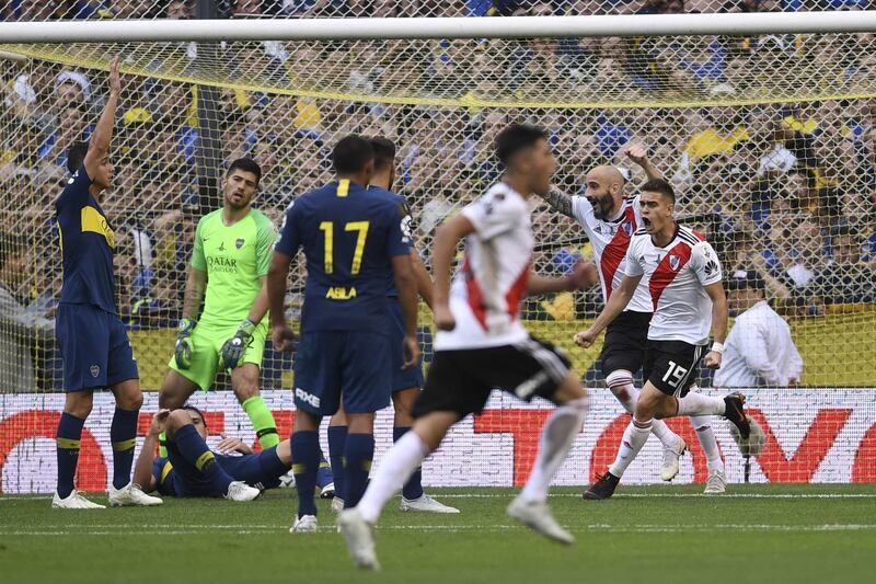 River Plate's Colombian Rafael Santos Borre (R) and teammate Javier Pinola celebrate an own goal by Boca Juniors' Carlos Izquierdoz (L, on the ground) during their first leg match of the all-Argentine Copa Libertadores final, at La Bombonera stadium in Buenos Aires, on November 11, 2018. / AFP / Eitan ABRAMOVICH
