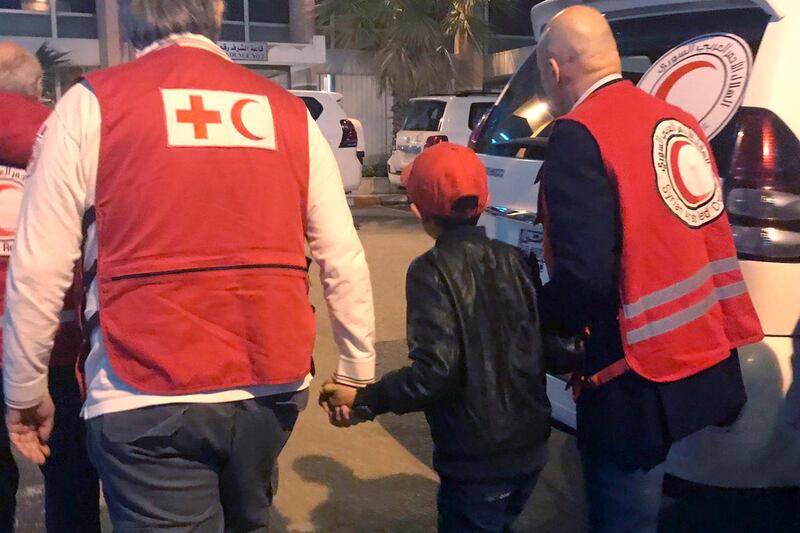 In this photo taken Wednesday, Nov. 6, 2019, Alvin, an 11-year-old Albanian boy who was taken to Syria by his mother when she joined the Islamic State group, is accompanied to Damascus airport by Red Cross and Red Crescent officials, after he was freed from a crowded detention camp. The boy, who found himself with no family in the al-Hol camp run by Kurdish forces in northeastern Syria after his mother and siblings died amid fighting, is heading home, to Italy, where his father lives. (International Federation of Red Cross and Red Crescent photo via AP)