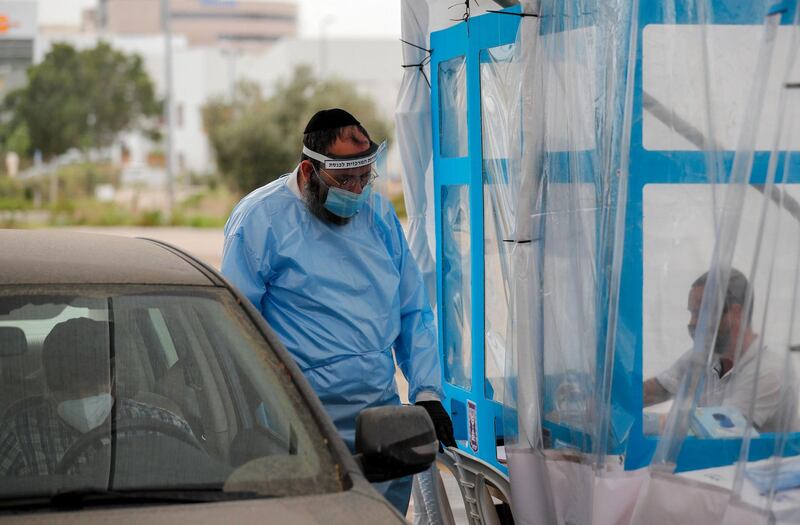 An Israeli electoral worker, clad in full protective gear against the spread of the COVID-19 coronavirus, waits as a voter registers before casting his ballot at a drive-in polling station for quarantined people in the northern coastal city of Haifa. AFP