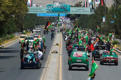 People ride in a convoy waving Afghan national flags along a street to celebrate the 100th anniversary of the country's Independence Day in Kabul on August 19, 2019. / AFP / Wakil KOHSAR
