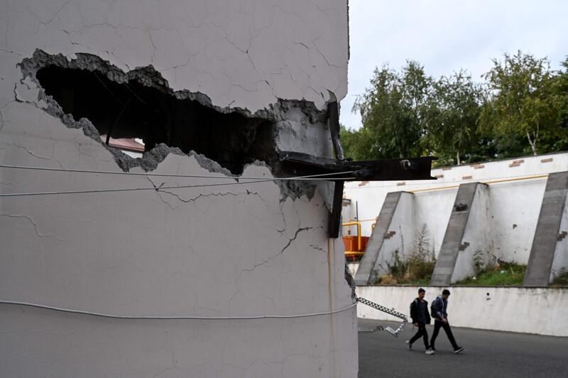 Two men walk past an apartment building damaged by shelling in the Nagorny Karabakh's main city of Stepanakert during the ongoing fighting between Armenia and Azerbaijan over the disputed region. AFP