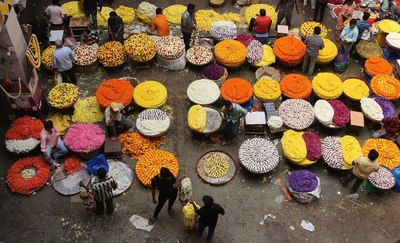 People buy flowers, fruits and essentials at a city market in Bengaluru. EPA