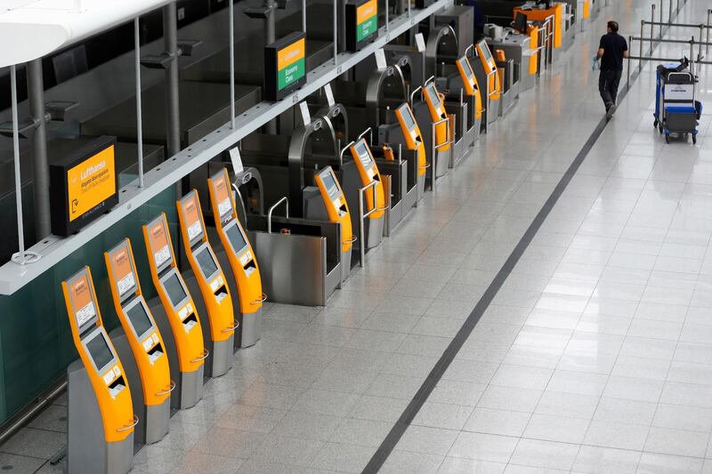 An airport employee cleans the check-in counter of German airline Lufthansa in Munich, Germany, Tuesday, May 26, 2020. Germany on Monday approved a 9 billion-euro ($9.8 billion) aid package for stricken airline Lufthansa to keep a major employer going through the turbulence of the coronavirus pandemic. (AP Photo/Matthias Schrader)