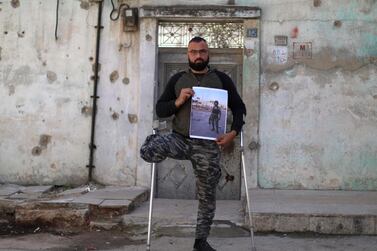 Mohammed Al Hamid, a 28-year-old former Syrian rebel fighter and amputee, poses for a picture while leaning on crutches in the rebel-held northern city of Idlib on March 6, 2021, while holding a large picture of himself before the war in a military uniform and holding a weapon. Mr Al Hamid says he was wounded in a 2016 battle against government forces in Latakia, where his brother also died in his arms. That same year, he learnt three other siblings had died in prison after they were detained two years earlier. In 2017, war planes bombarded his home in Idlib, killing his daughter. AFP.
