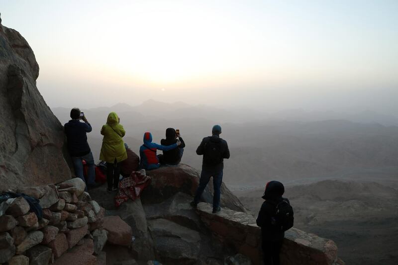 Tourists watch the sunrise outside a church on the top of Mount Moses, in Saint Catherine city in Egypt's South Sinai Governorate. EPA