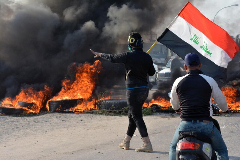 A demonstrator holds an Iraqi flag near  burning tires during ongoing anti-government protests in Nassiriya, Iraq November 24, 2019. REUTERS/Ahmed Dhahi NO RESALES. NO ARCHIVES