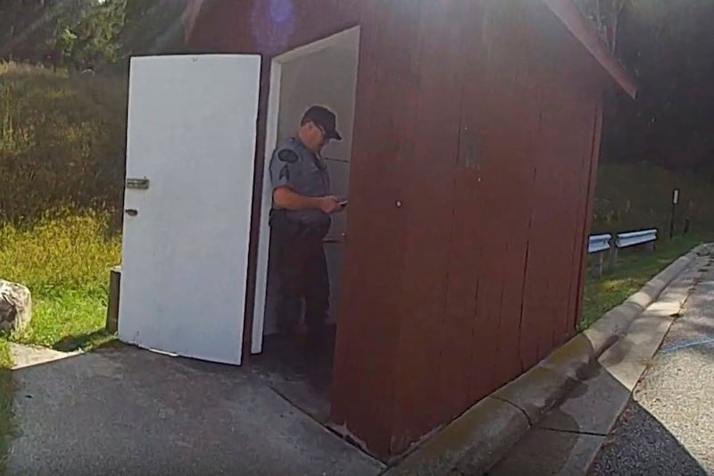 An officer stands in the doorway of an outhouse in Michigan after a woman became trapped in the toilet. Michigan State Police / AP
