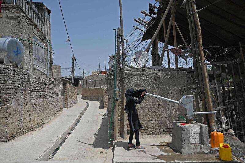 A girl uses a hand pump to fill a container with drinking water in Kabul, Afghanistan.