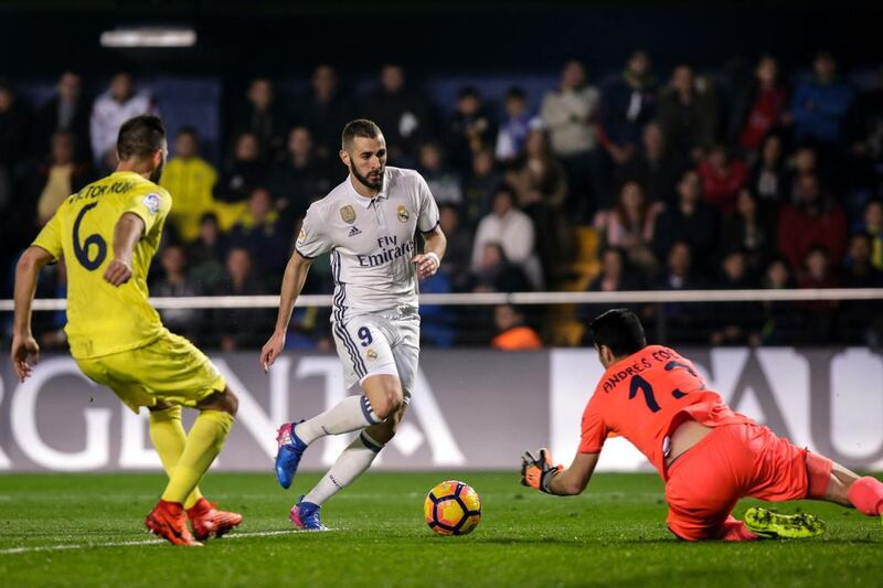 Real Madrid forward Karim Benzema, centre, vies with Villarreal’s goalkeeper Aitor Fernandez. Biel Alino / AFP