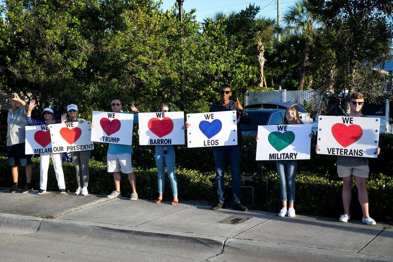 Supporters hold signs as Donald Trump's motorcade heads to his Mar-a-Lago club, in West Palm Beach, Florida, April 18, 2019. Reuters