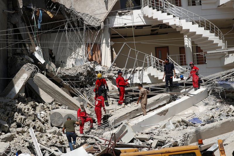 Firefighters remove debris from the site of the collapsed building on Saturday. Reuters