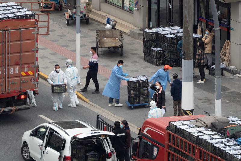 Workers in PPE unload groceries from a truck before distributing them to local residents under Covid-19 lockdown in Shanghai on Tuesday. AP